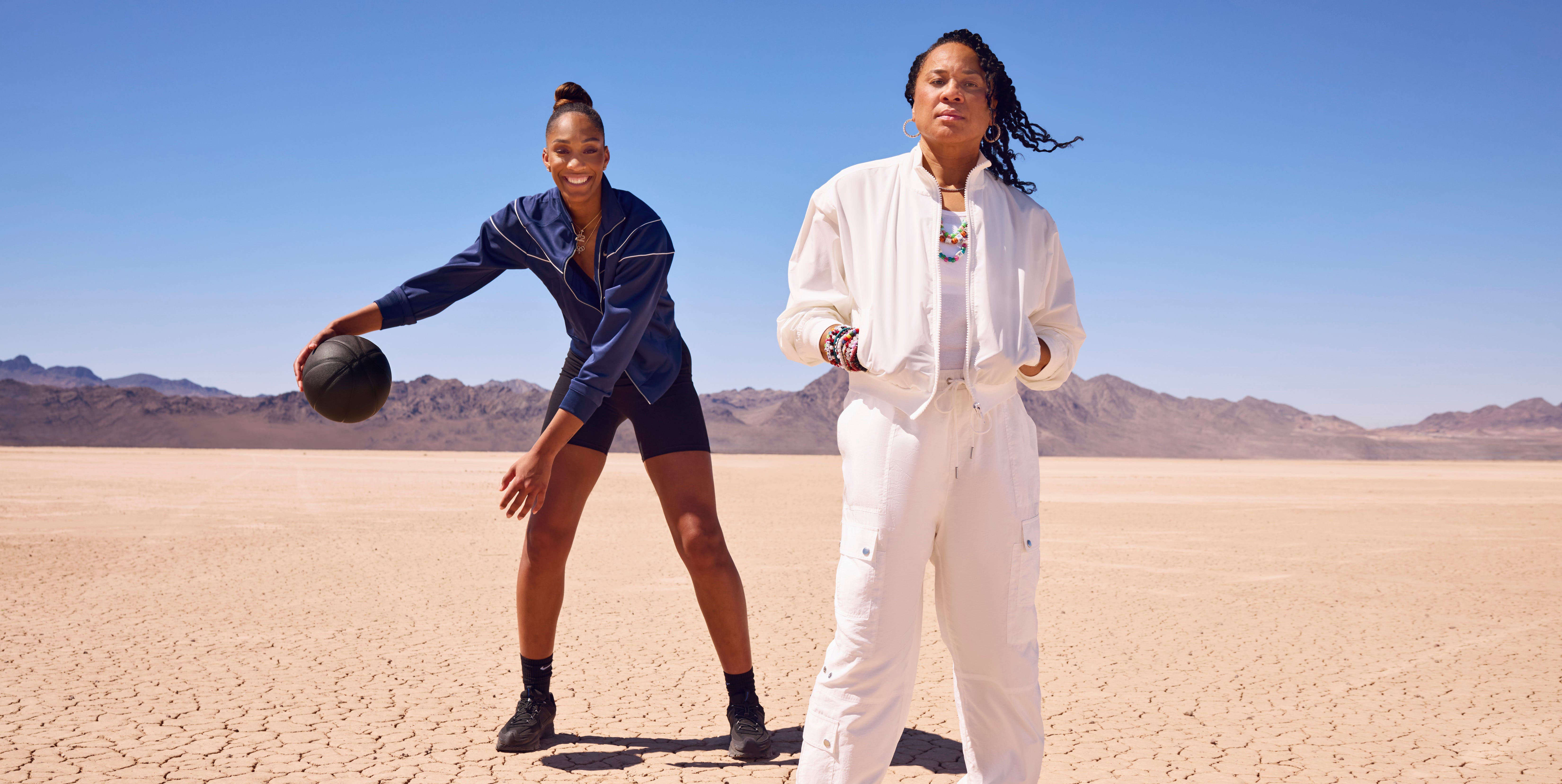 two individuals dressed in athletic apparel on a dry cracked terrain indicating a desert environment