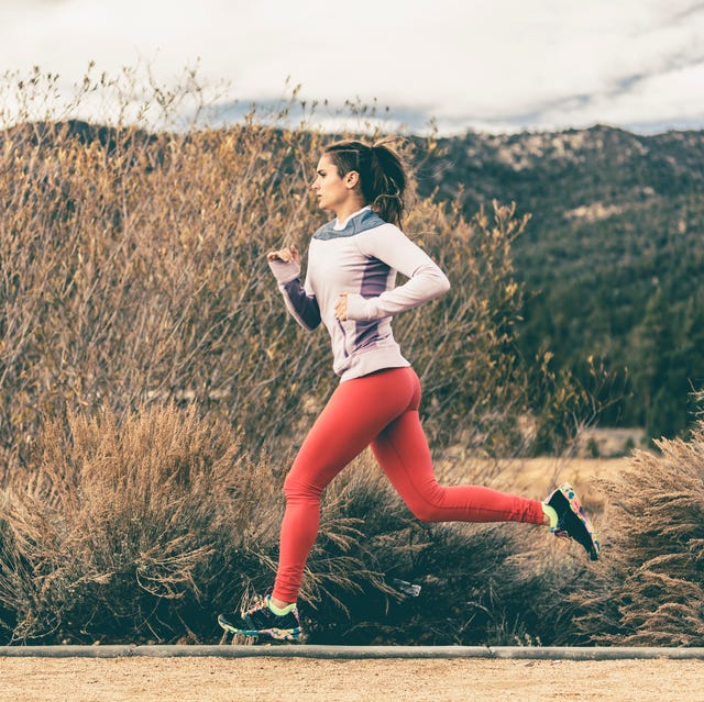 side view of female athlete running by field