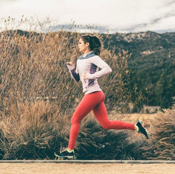 side view of female athlete running by field
