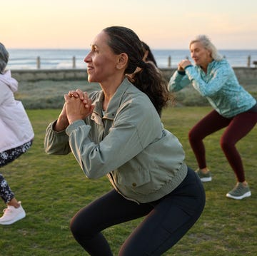 smiling woman squatting while doing exercise with friends