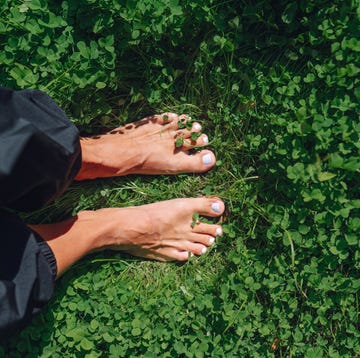 eco lawn. bare feet of woman walking on green clover leaves