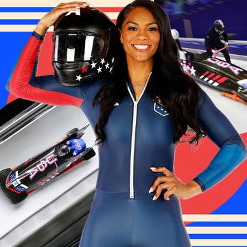 female athlete in a racing suit holding a helmet with a bobsled scene in the background