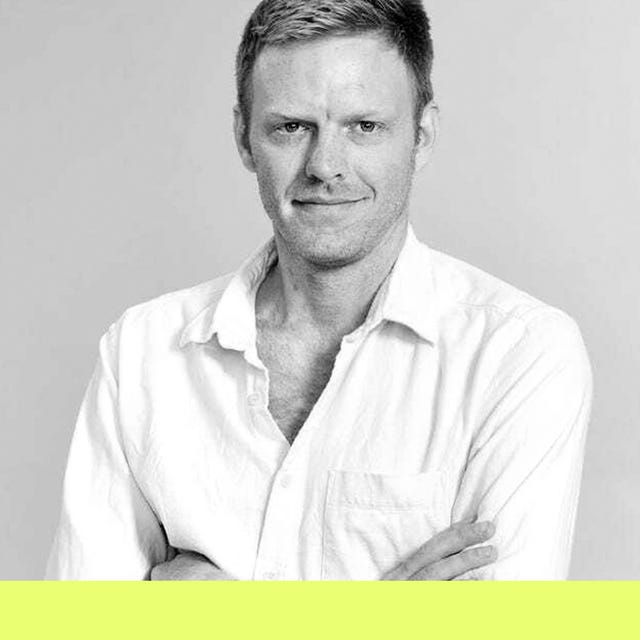 male figure in a white shirt with arms crossed against a minimalist background