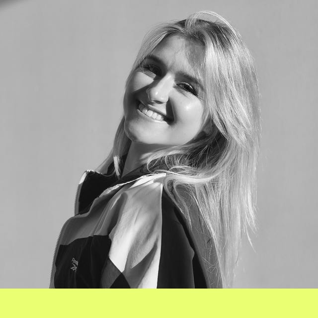 portrait of a person with long hair wearing a colorful jacket against a neutral background