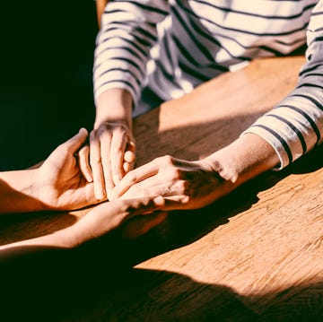 two unrecognizable persons holding each others hands. concept of emotional support during hard times from family and friends, conquering adversities together.