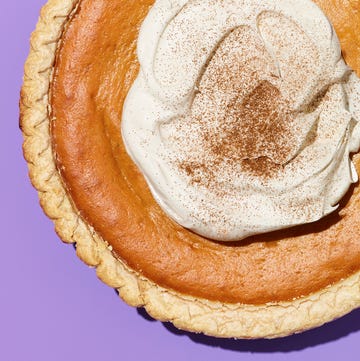 Pumpkin pie topped with whipped cream and cinnamon on a purple background