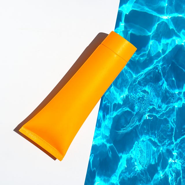 orange tube with suntan lotion, cosmetic face cream or hand cream, shower gel, shampoo against the background of blue turquoise water with waves from the swimming pool. body, hair skin care nature concept. flat lay. copy space. close up.