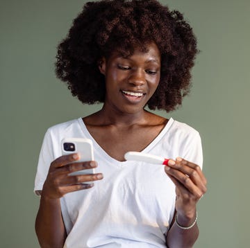 person holding a smartphone and a pregnancy test
