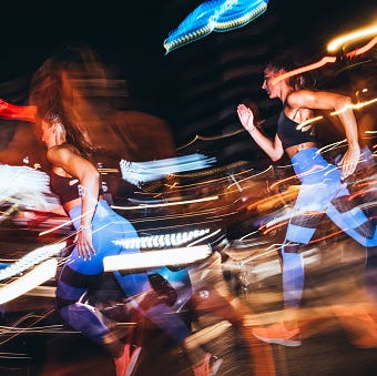 dynamic scene of two women sprinting through a city at night showcasing movement and energy