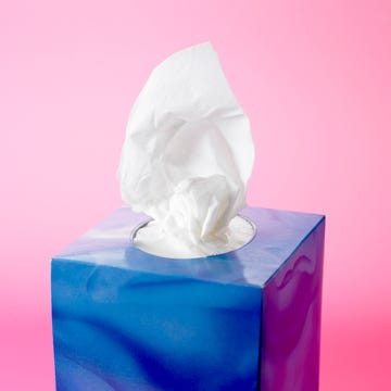 tissue box with tissues partially pulled out set against a pink background