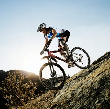 mountain biker ascending a rocky slope under a clear sky