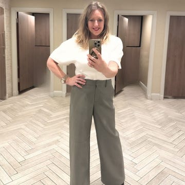 person posing in a fitting room wearing a white top and green pants