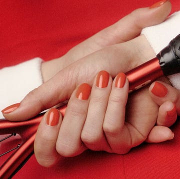 hands holding a tennis racket featuring manicured nails