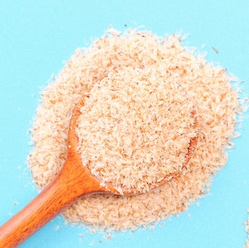 two wooden spoons of psyllium husk on a blue background top view, close up.
