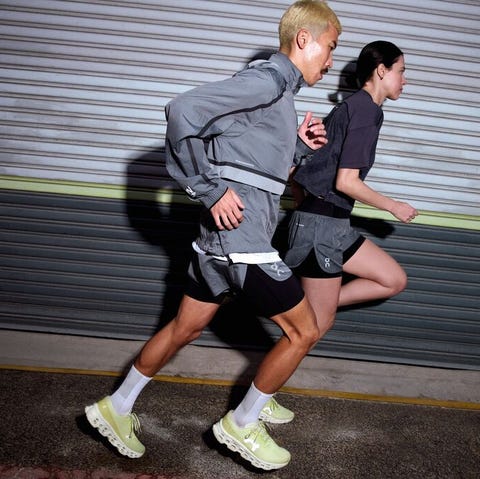 two individuals running in athletic attire against a backdrop of a metal surface
