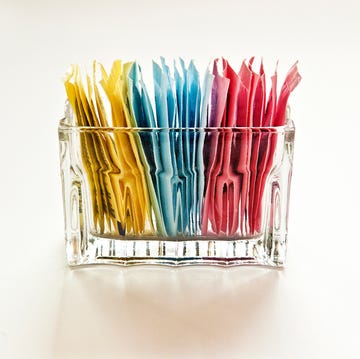 artificial sweeteners in a clear glass container on a white, cut out, background