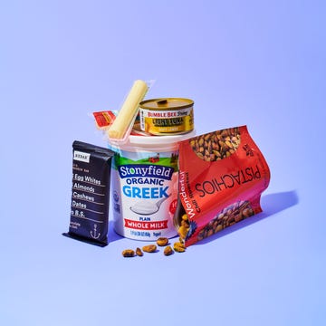 multiple snacks, such as string cheese and pistachios, on a blueish purple background