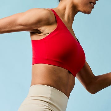 athlete in motion wearing a red sports bra and beige leggings