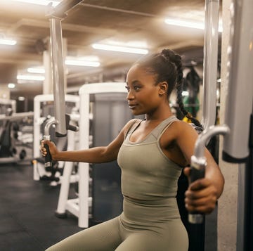 strong african american sportswoman is exercising chest on pectoral fly machine at gym.