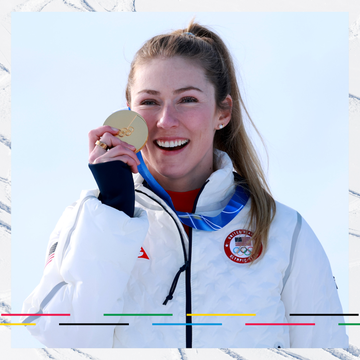 athlete holding a gold medal against a snowy background